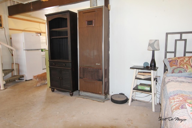 bedroom with concrete flooring and white fridge