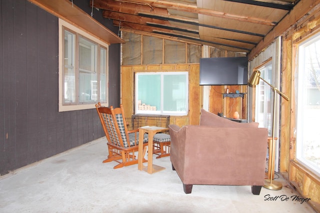 interior space with concrete flooring, vaulted ceiling, and wood walls