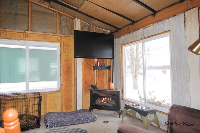 living room with wooden ceiling, lofted ceiling, concrete flooring, and a wood stove