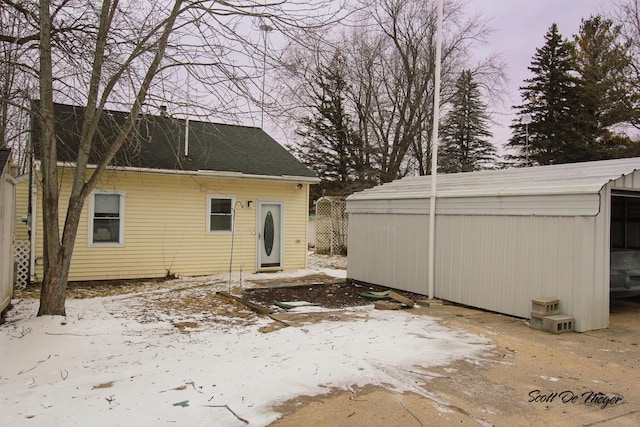 snow covered property with an outbuilding