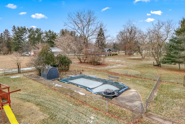 view of yard featuring a rural view, a playground, and a storage unit