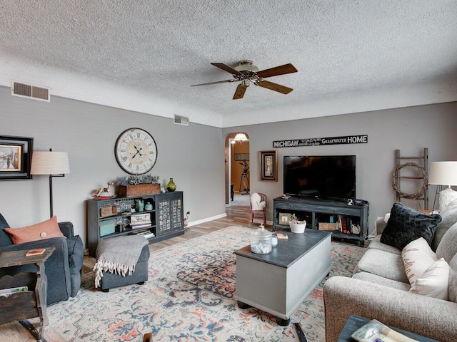 living room with hardwood / wood-style floors, a textured ceiling, and ceiling fan