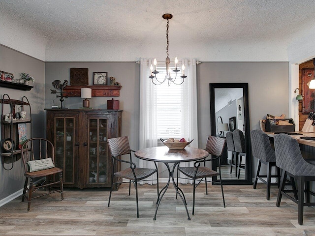 dining space with an inviting chandelier, light hardwood / wood-style flooring, and a textured ceiling