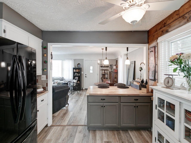 kitchen featuring gray cabinetry, decorative light fixtures, light hardwood / wood-style flooring, black refrigerator, and white cabinets