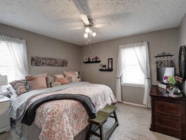 carpeted bedroom with ceiling fan and a textured ceiling