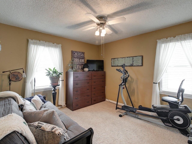 workout area featuring ceiling fan, light carpet, and a textured ceiling