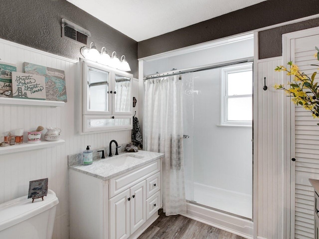 bathroom featuring vanity, toilet, a shower with door, and hardwood / wood-style floors