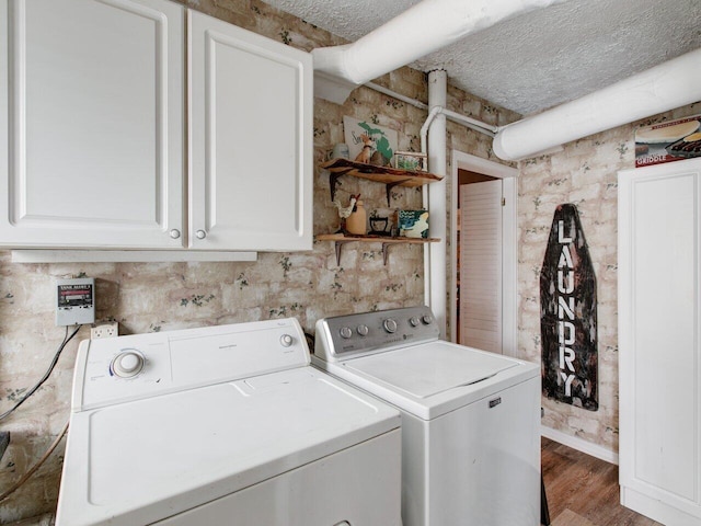 laundry area featuring cabinets, wood-type flooring, a textured ceiling, and washer and clothes dryer