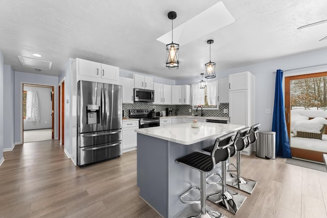 kitchen with a kitchen island, appliances with stainless steel finishes, white cabinets, and a kitchen breakfast bar