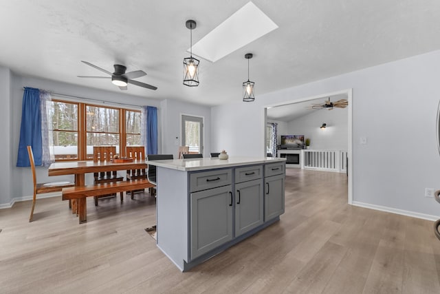 kitchen featuring decorative light fixtures, gray cabinets, light hardwood / wood-style flooring, and a wealth of natural light