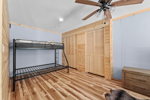 unfurnished bedroom with ceiling fan, light hardwood / wood-style floors, and multiple closets