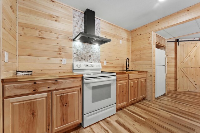 kitchen with white appliances, wall chimney exhaust hood, a barn door, and butcher block countertops