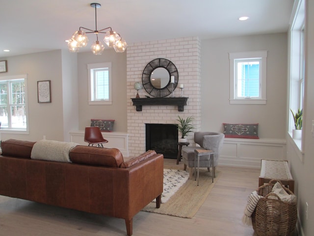 living room with a brick fireplace, a wealth of natural light, and light hardwood / wood-style flooring