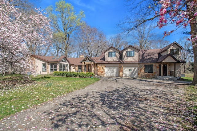 view of front facade featuring a garage, stone siding, aphalt driveway, and a front lawn