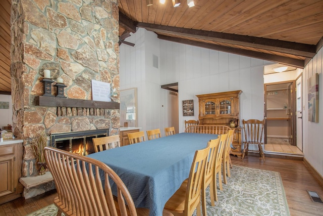 dining area featuring beam ceiling, a fireplace, wood finished floors, and visible vents
