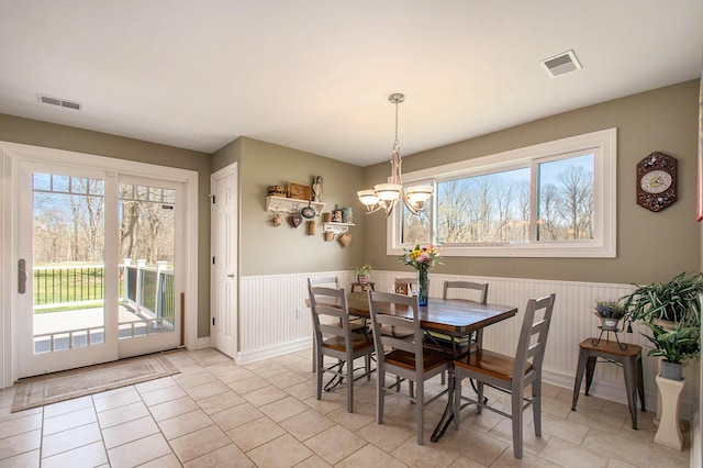 dining room featuring wainscoting, visible vents, and an inviting chandelier