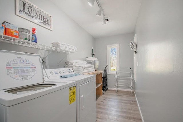 washroom featuring light wood finished floors, laundry area, baseboards, washer and dryer, and track lighting