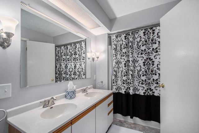 bathroom with curtained shower, a sink, and double vanity