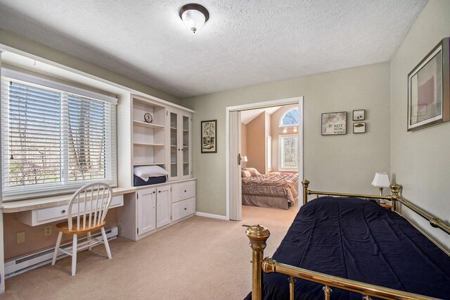 bedroom featuring a baseboard heating unit, built in study area, light carpet, a textured ceiling, and baseboards