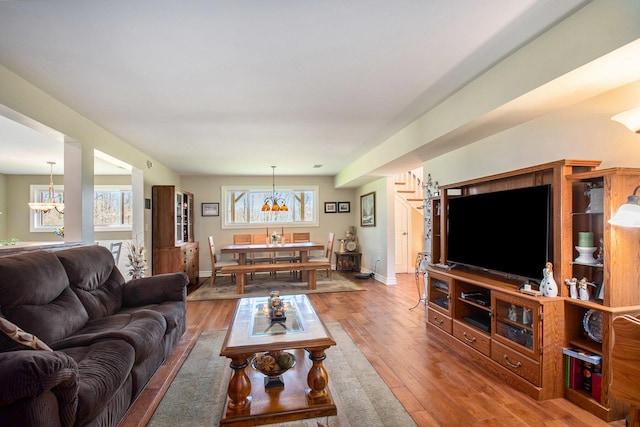 living room with baseboards, wood finished floors, and an inviting chandelier
