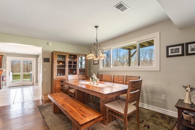 dining space with baseboards, wood-type flooring, visible vents, and a notable chandelier