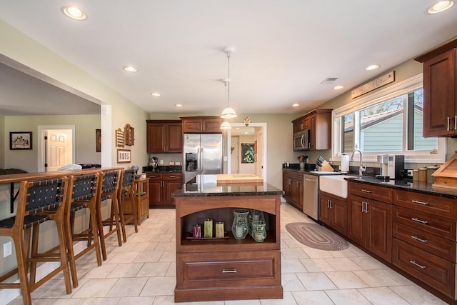 kitchen featuring recessed lighting, a kitchen island, a sink, hanging light fixtures, and appliances with stainless steel finishes