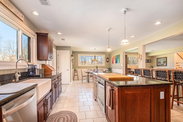 kitchen featuring plenty of natural light, a sink, stainless steel dishwasher, and light tile patterned floors