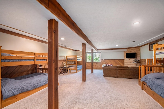 carpeted bedroom with recessed lighting, beam ceiling, a wainscoted wall, and wooden walls