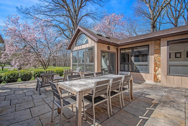 view of patio with a sunroom and outdoor dining area