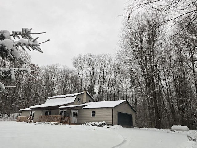 snow covered property with a garage and covered porch