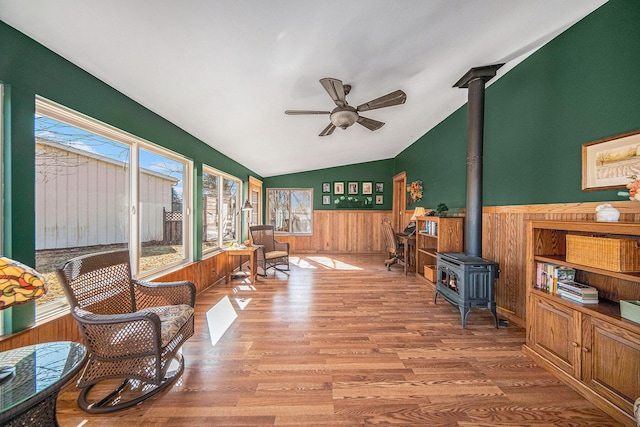 sunroom / solarium with lofted ceiling, a wood stove, and a ceiling fan