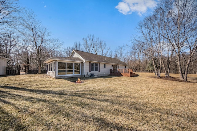 back of property featuring fence, a wooden deck, a lawn, cooling unit, and a sunroom