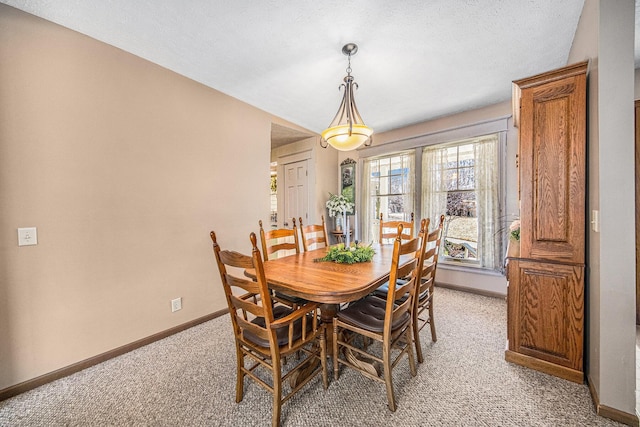 dining area with light colored carpet, a textured ceiling, and baseboards