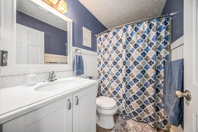 bathroom featuring vanity, a shower with curtain, wainscoting, a textured ceiling, and toilet