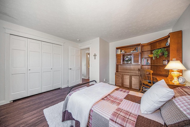 bedroom with a closet, baseboards, a textured ceiling, and wood finished floors