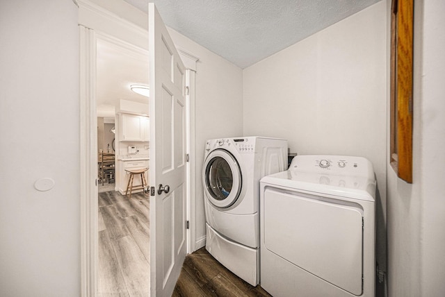 laundry room featuring laundry area, washer and dryer, a textured ceiling, and dark wood-type flooring