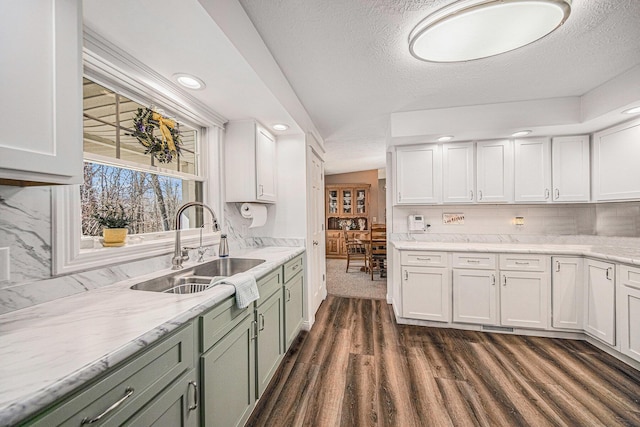 kitchen featuring dark wood-style floors, a sink, white cabinets, a textured ceiling, and backsplash