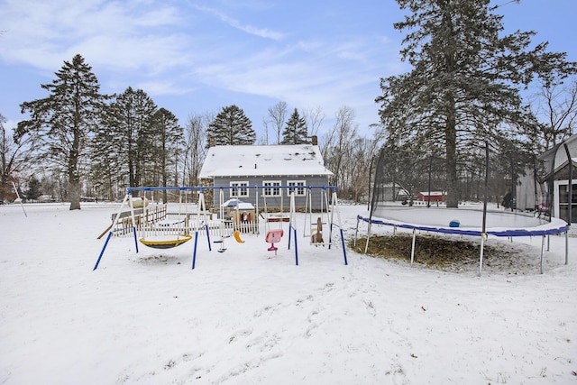 snow covered back of property featuring a playground and a trampoline