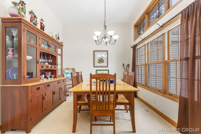 dining room with light colored carpet and a chandelier