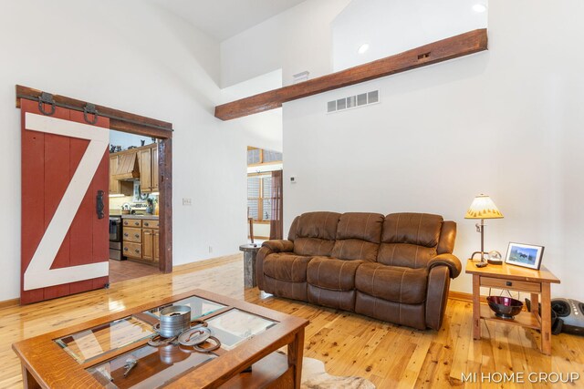 living room featuring a high ceiling, wood-type flooring, and a barn door