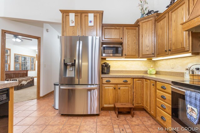 kitchen with light tile patterned flooring, tasteful backsplash, appliances with stainless steel finishes, custom range hood, and ceiling fan