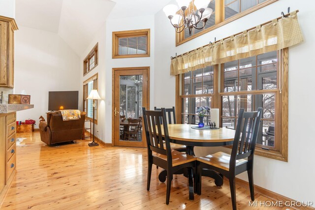 dining room featuring a chandelier, high vaulted ceiling, and light wood-type flooring