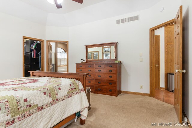 carpeted bedroom featuring a walk in closet, a closet, and ceiling fan