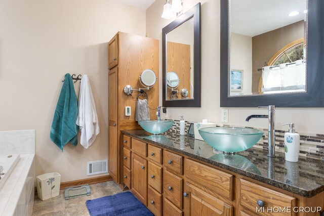 bathroom featuring vanity, tiled bath, and tile patterned flooring