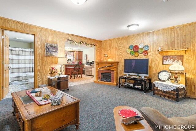 carpeted living room with a fireplace and wood walls