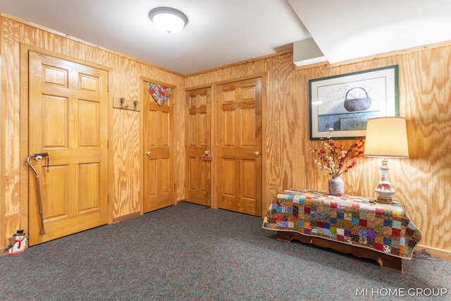 bedroom with wooden walls, ornamental molding, and dark colored carpet