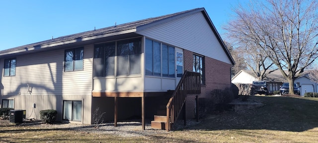 rear view of property featuring stairs, central AC, brick siding, and a sunroom