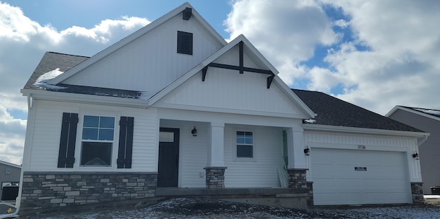 view of front facade with roof with shingles, a porch, a garage, cooling unit, and stone siding