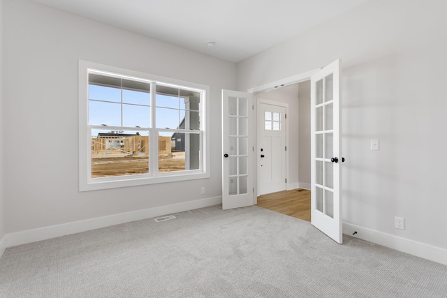 unfurnished room with french doors, light colored carpet, and a healthy amount of sunlight