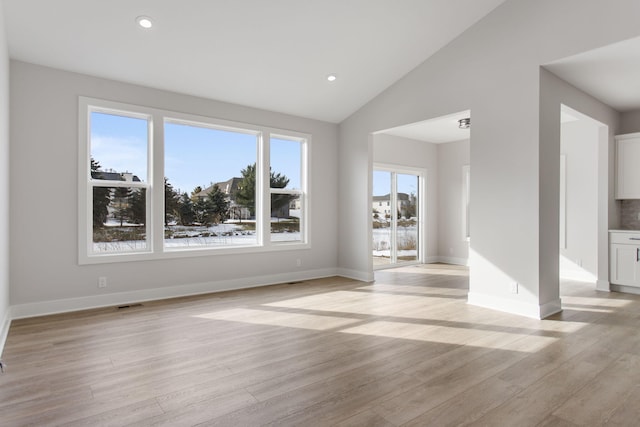 unfurnished living room featuring vaulted ceiling and light hardwood / wood-style flooring